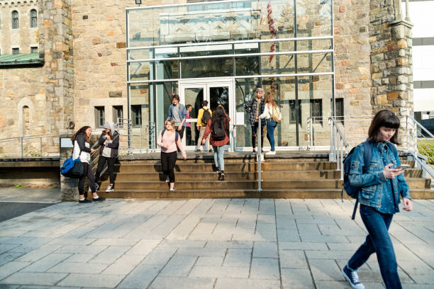 カナダの学生たちが学校から携帯をいじりながら友達と楽しそうに話しているカナダライフ